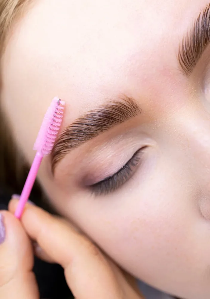 Brow lamination being finished with a spoolie brush